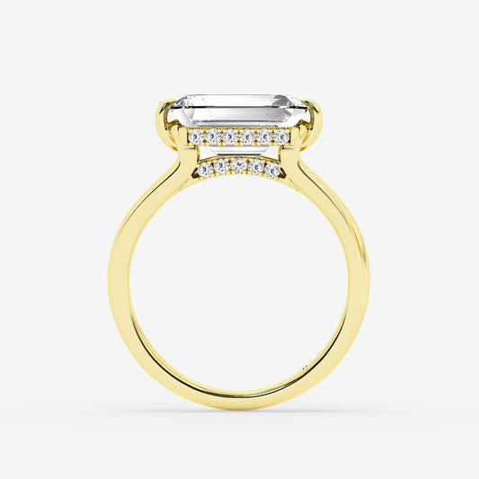 Gold ring with a large emerald-cut center stone and smaller diamonds on a white background