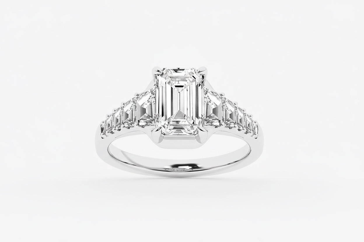 Diamond ring with emerald-cut center stone and baguette side stones on a white background