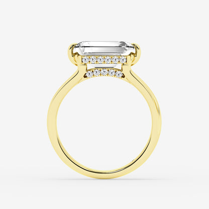 Gold ring with a large emerald-cut center stone and smaller diamonds on a white background