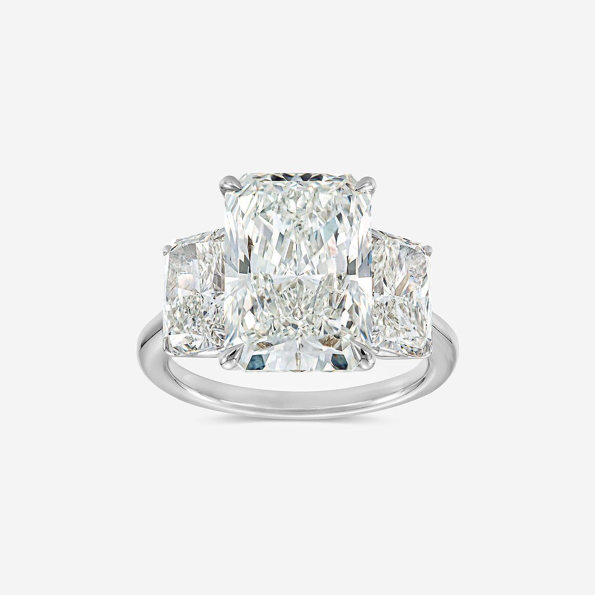 Diamond ring with three prominent diamonds on a light gray background