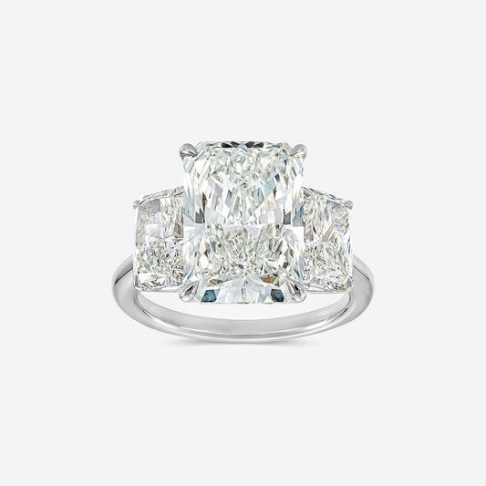 Diamond ring with three prominent diamonds on a light gray background
