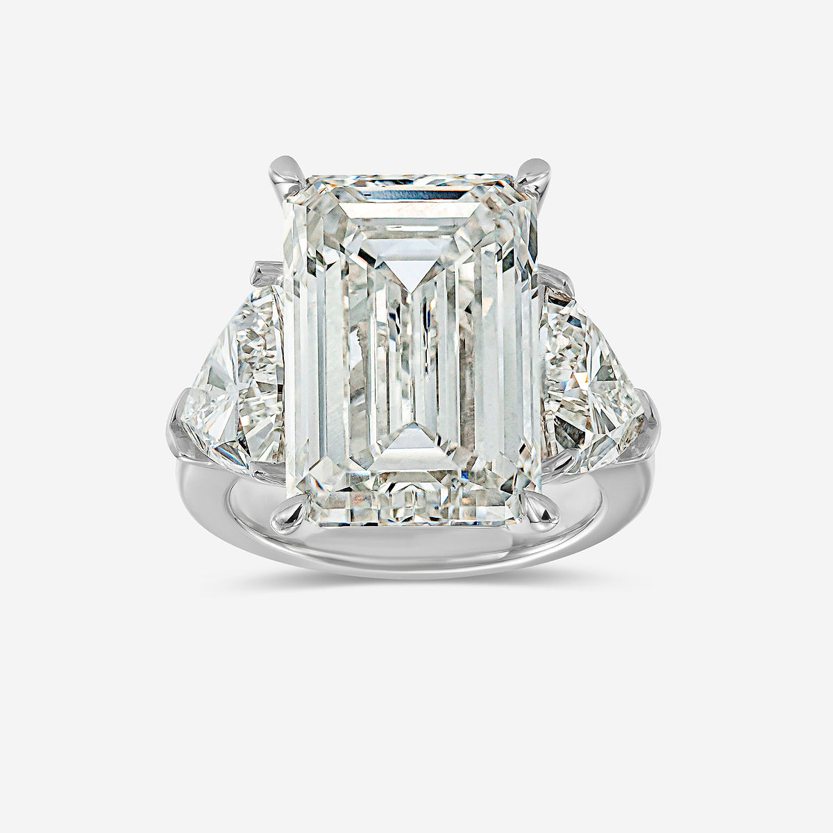 Diamond ring with emerald-cut center stone on a white background
