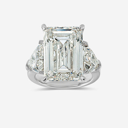 Diamond ring with emerald-cut center stone on a white background
