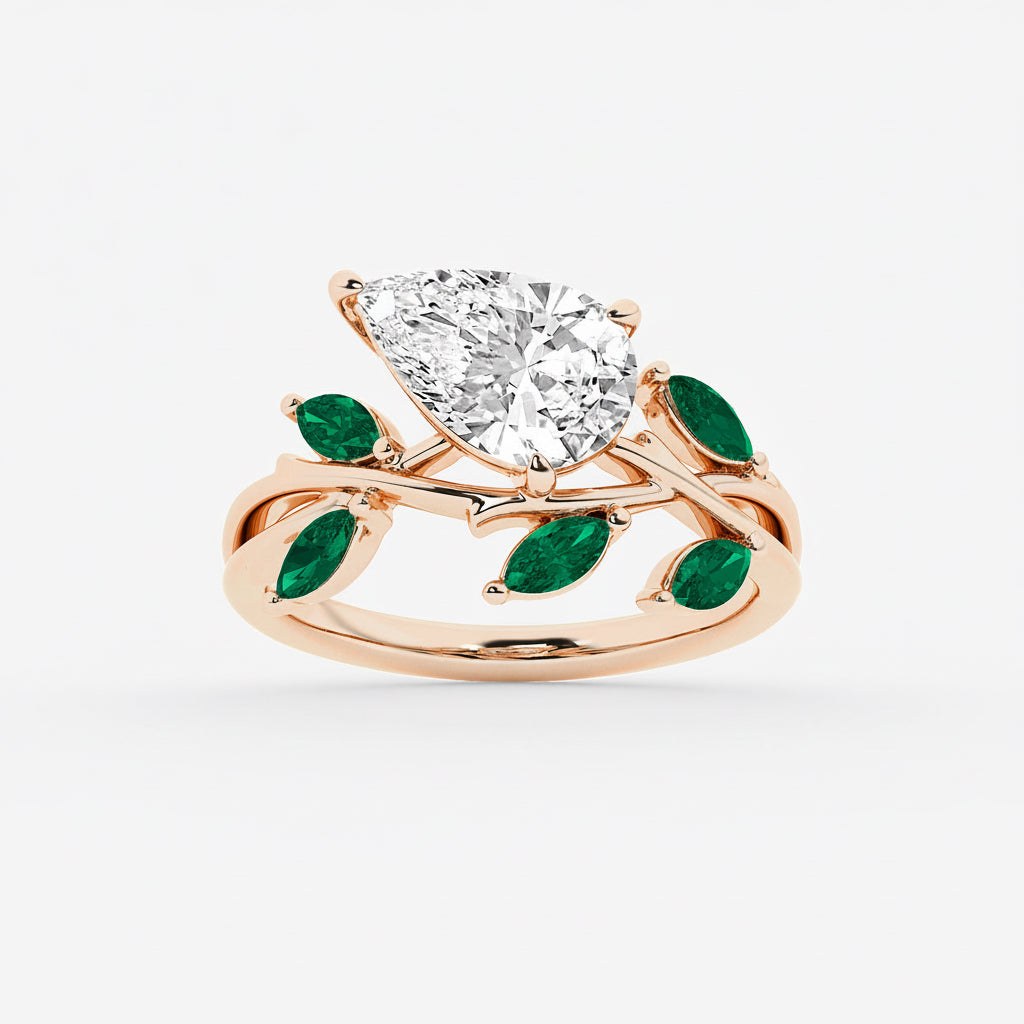 Rose gold ring with a large diamond and green gemstones on a white background