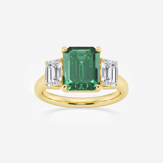 Gold ring with a green emerald and two white diamonds on a light gray background