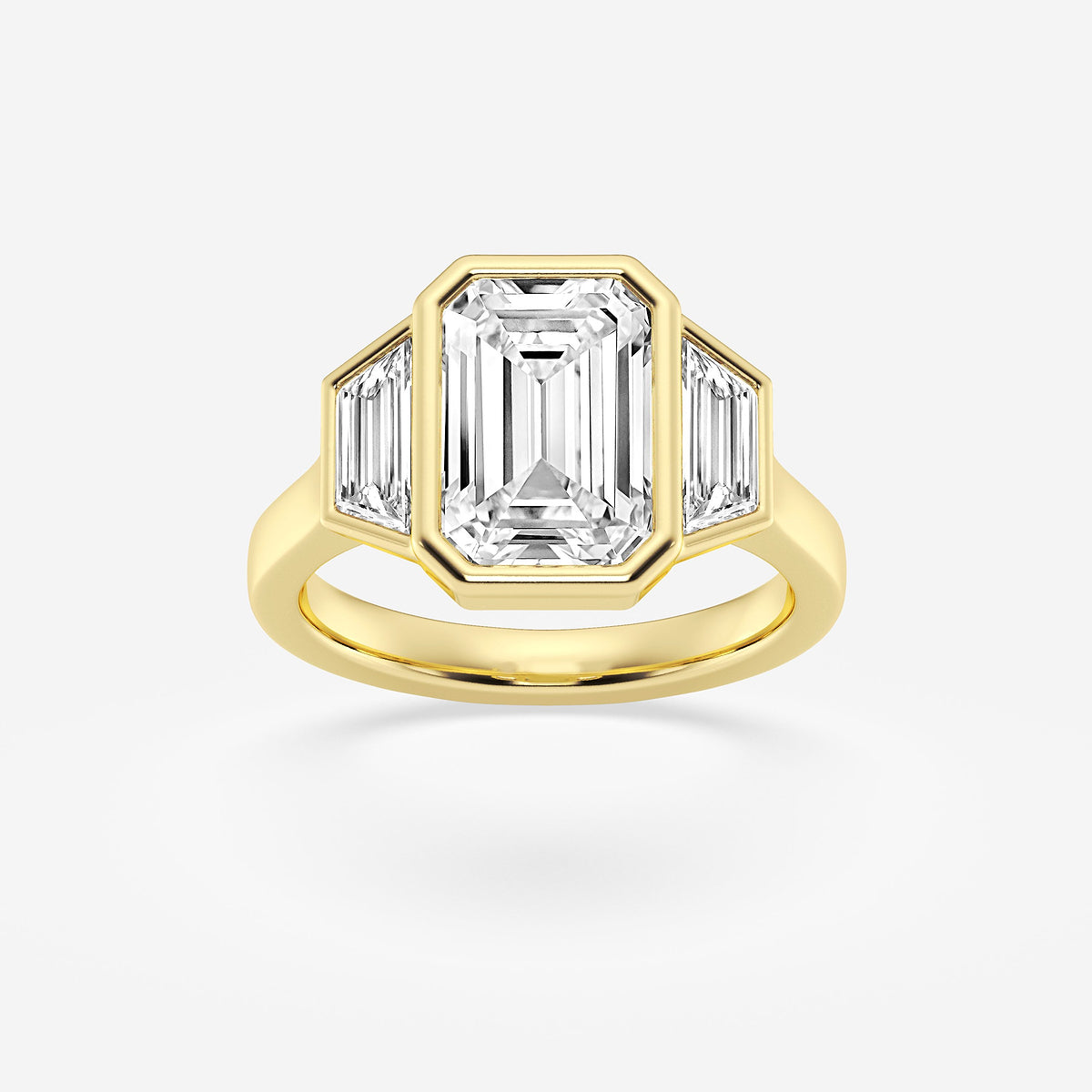 Gold ring with emerald-cut diamond and baguette side stones on a white background